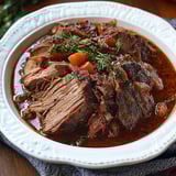 A plate of beef stew with carrots and parsley.